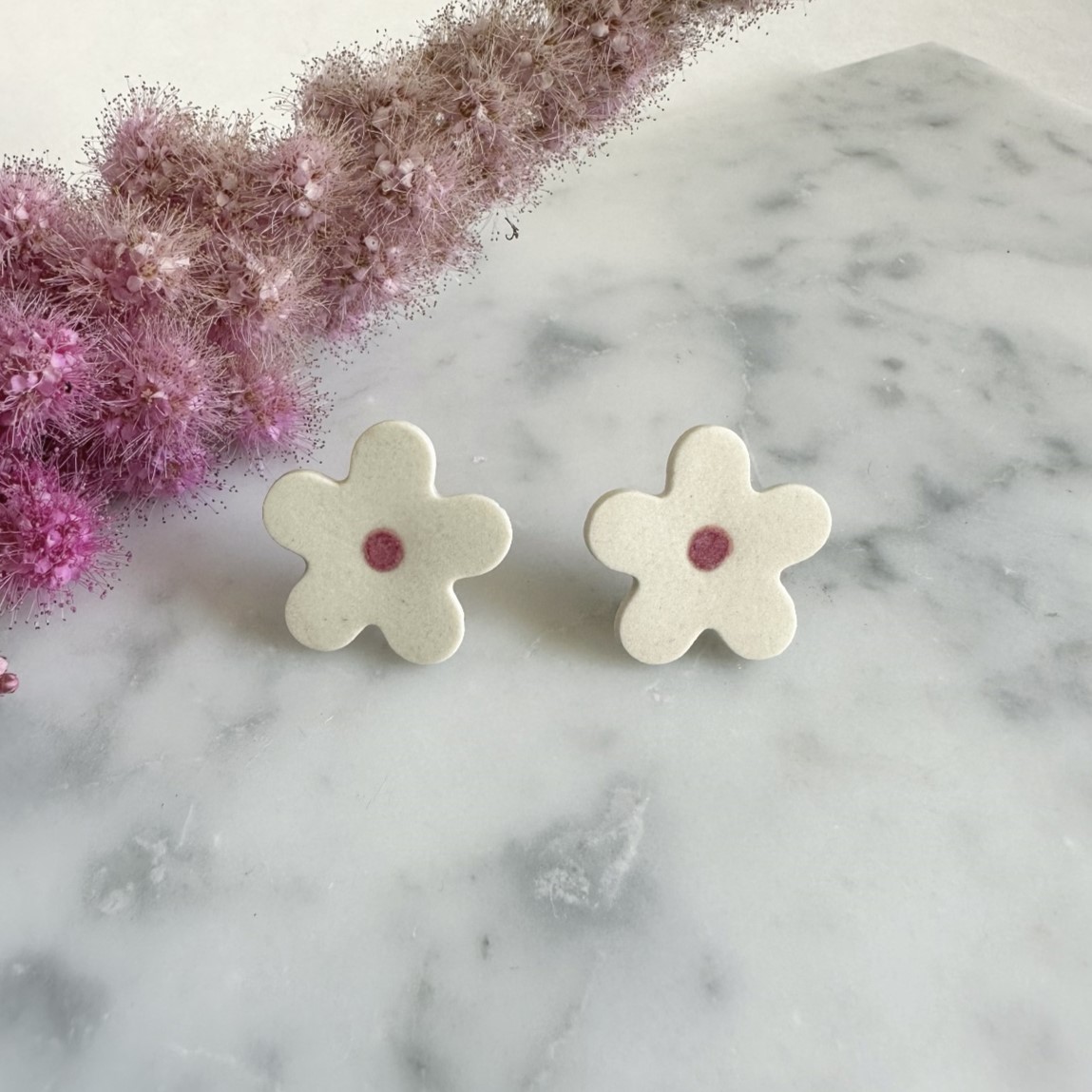 Two earrings shaped like five-petal white flowers